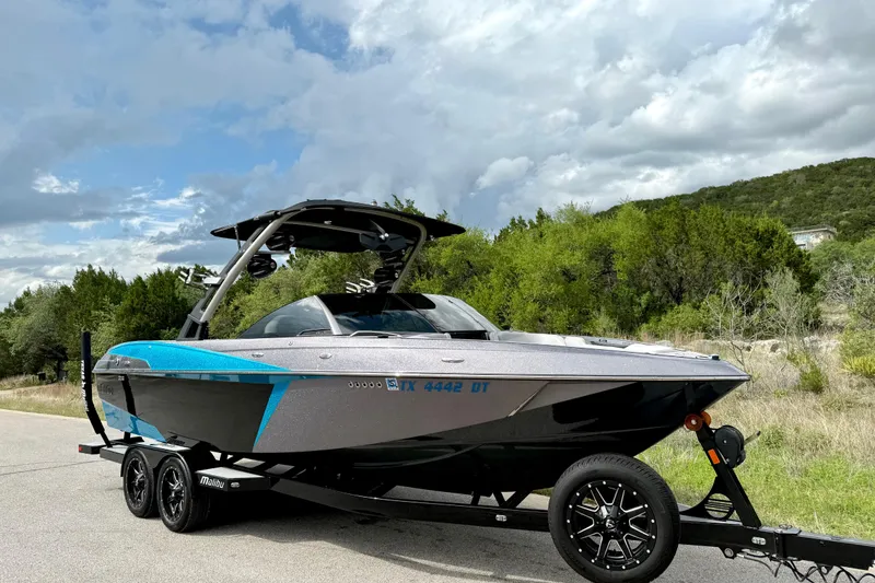 Slide: The Image of 2016 Malibu Wakesetter 25 LSV boat on trailer, parked on a scenic road. - 13