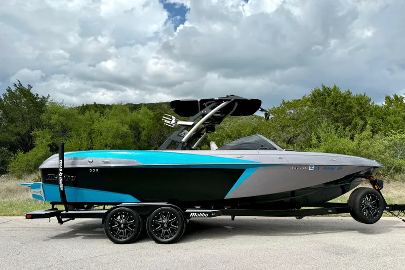 Slide: The Image of 2016 Malibu Wakesetter 25 LSV boat on trailer, parked outdoors under cloudy sky. - 14