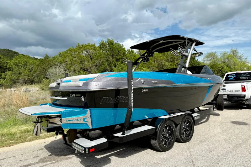 Slide: The Image of 2016 Malibu Wakesetter 25 LSV boat on trailer, parked outdoors under cloudy sky. - 15