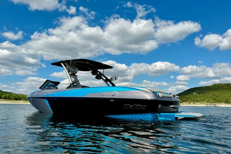 Slide: The Image of 2016 Malibu Wakesetter 25 LSV boat on a lake under a blue sky with clouds. - 6