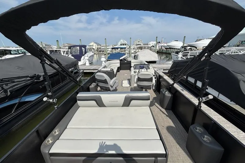 Slide: The Image of 2023 Viaggio LAGO 25S pontoon boat interior at marina, featuring seating and helm. - 7