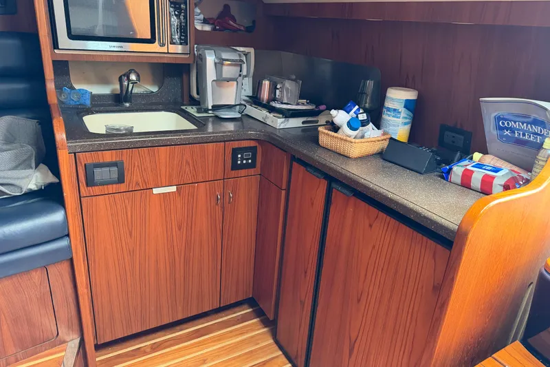 Slide: The Image of Compact kitchen area in a 2004 Tiara 3800 boat with wooden cabinetry and appliances. - 22