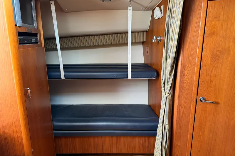 Slide: The Image of Bunk beds in a 2004 Tiara 3800 yacht cabin with wood paneling and striped curtain. - 23