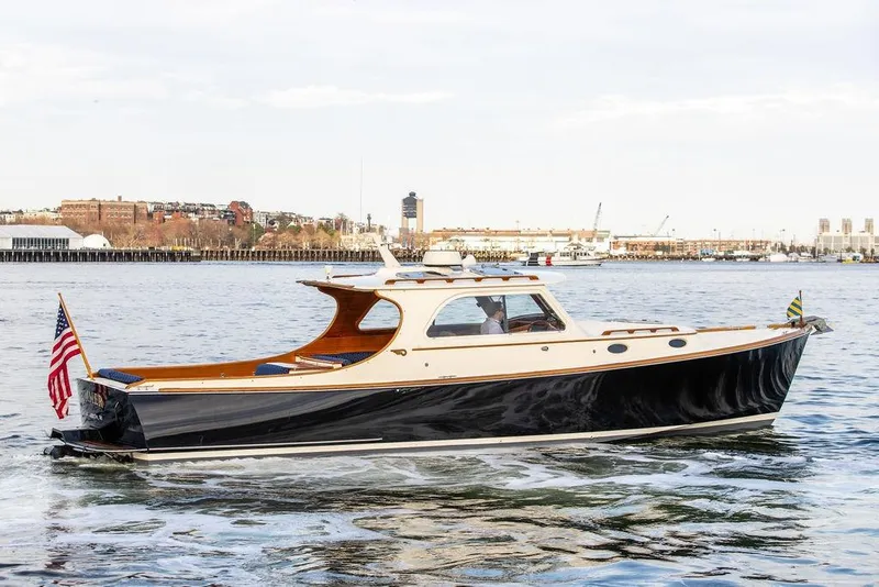 Slide: The Image of 2002 Hinckley Picnic Boat 36 EP cruising on a calm waterfront with cityscape background. - 2