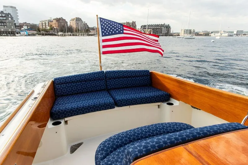 Slide: The Image of 2002 Hinckley Picnic Boat 36 EP with American flag, cruising on a scenic waterfront. - 24
