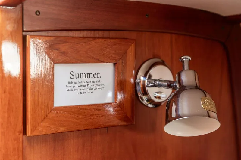 Slide: The Image of Wooden interior of 2002 Hinckley Picnic Boat 36 EP with framed "Summer" quote and chrome light fixture. - 28