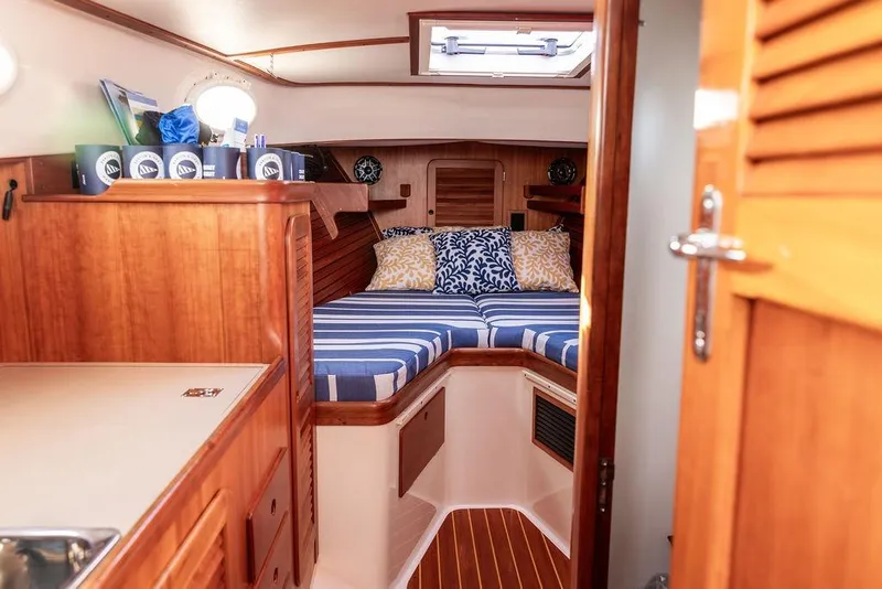 Slide: The Image of Interior of 2002 Hinckley Picnic Boat 36 EP with cozy cabin and striped bedding. - 32