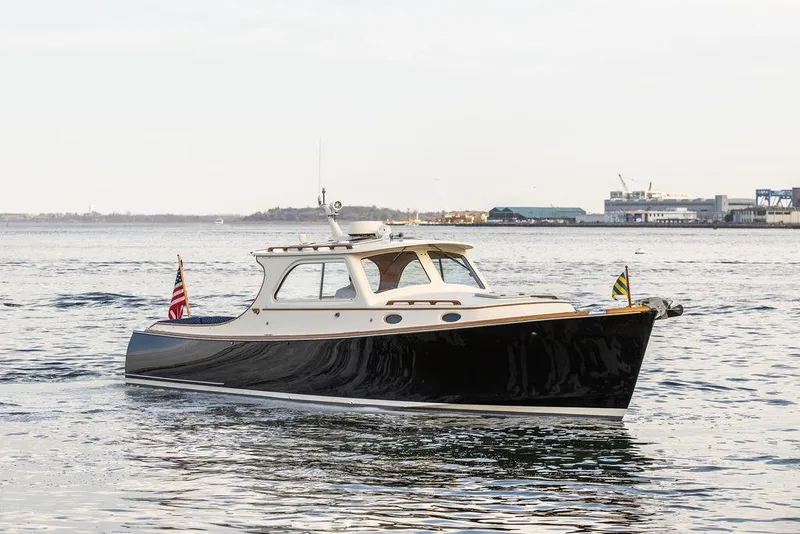 Slide: The Image of 2002 Hinckley Picnic Boat 36 EP cruising on calm waters near a coastal cityscape. - 43