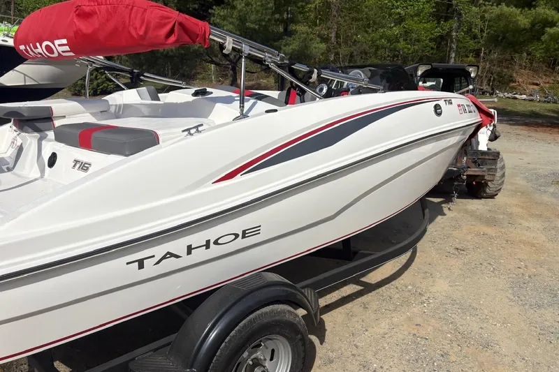 Slide: The Image of 2022 Tahoe T16 boat on trailer, white with red accents, parked outdoors. - 4