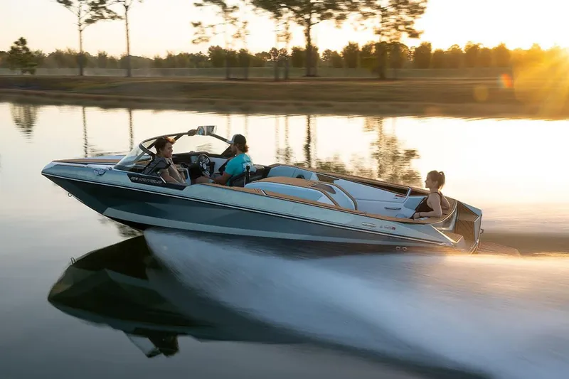 Slide: The Image of Manufacturer Provided Image: 2024 Nautique Ski boat cruising on a serene lake at sunset. - 5