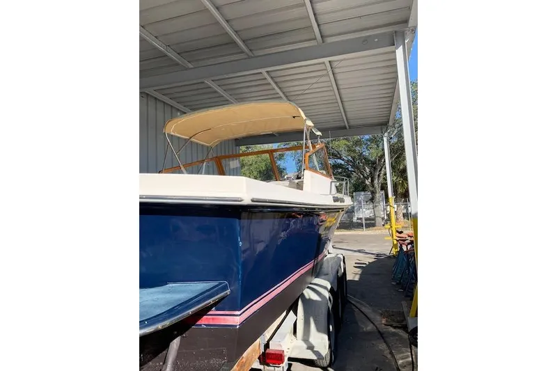 Slide: The Image of 1999 Nauset Downeast Cruiser boat under a metal canopy, featuring a blue hull and beige canopy. - 4