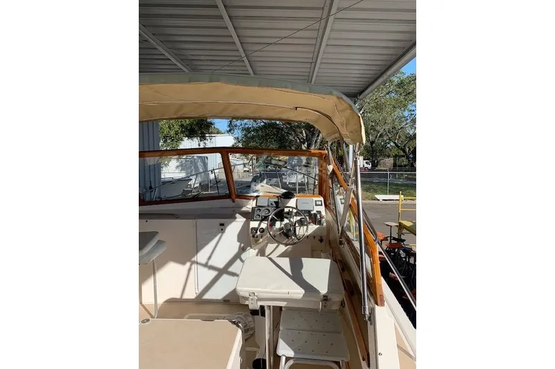 Slide: The Image of 1999 Nauset Downeast Cruiser boat interior with steering wheel and canopy under shelter. - 6