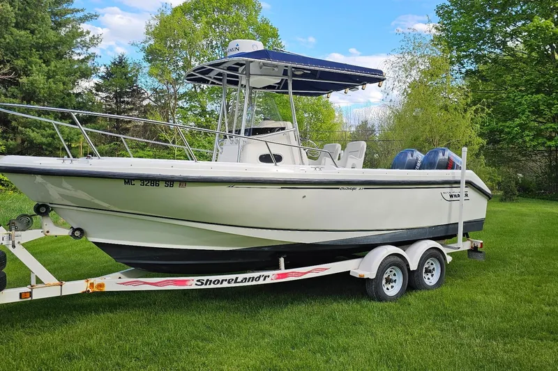 The Image of 1999 Boston Whaler 23 Outrage boat on trailer, parked on grass with trees in background. - 0