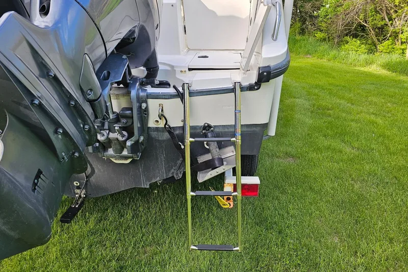 Slide: The Image of 1999 Boston Whaler 23 Outrage boat with ladder and motor on grassy area. - 3