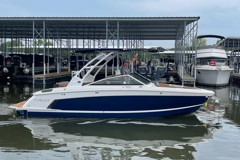 The Image of 2023 Cobalt R6 Surf boat docked at marina, featuring sleek design and blue hull. - 1