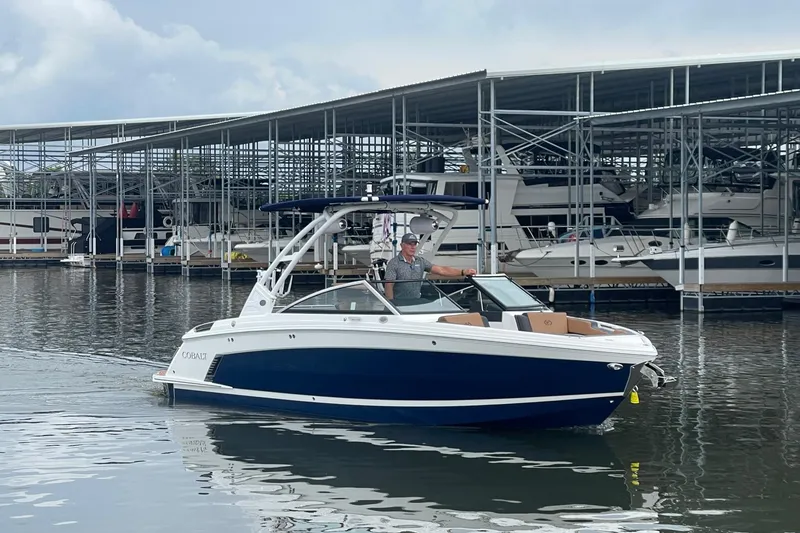 Slide: The Image of 2023 Cobalt R6 Surf boat docked at marina with covered slips in background. - 20