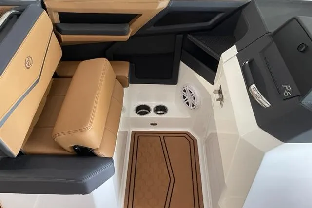 Slide: The Image of 2023 Cobalt R6 Surf boat interior with tan and black seating, speaker, and cup holders. - 6