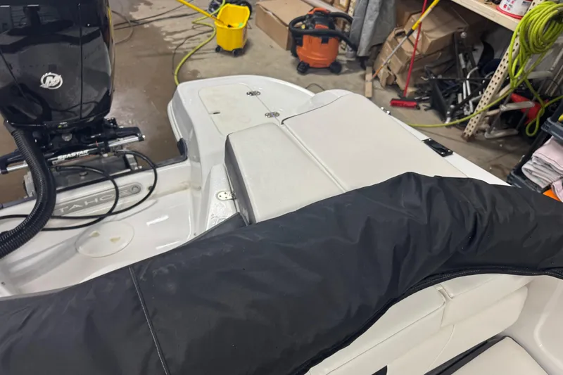 Slide: The Image of 2023 Tahoe 200 S boat interior with motor, in a garage setting. - 11