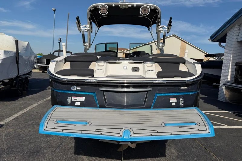 Slide: The Image of 2018 MasterCraft X26 boat with swim platform, parked outdoors under clear sky. - 3