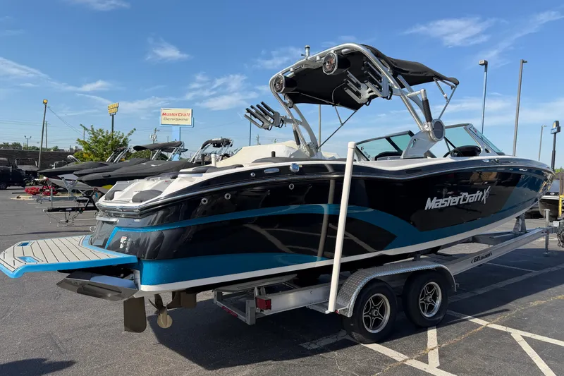 Slide: The Image of 2018 MasterCraft X26 boat on trailer in parking lot under clear blue sky. - 4