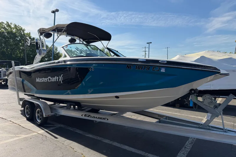 Slide: The Image of 2018 MasterCraft X26 boat on trailer, blue and white, parked outdoors. - 5
