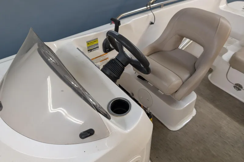 Slide: The Image of 2013 Hurricane SunDeck Sport 201 IO boat interior with steering wheel and beige captain's seat. - 6