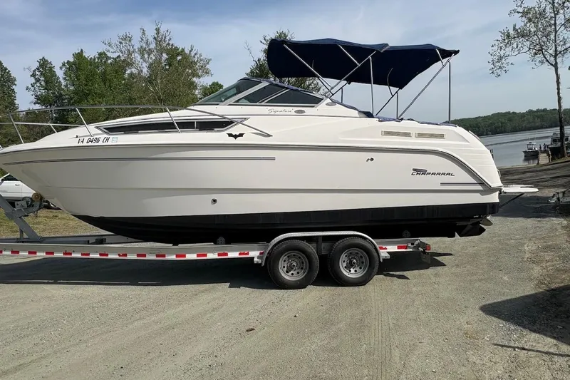 Slide: The Image of 2000 Chaparral Signature 270 boat on trailer, parked outdoors near a lake. - 2