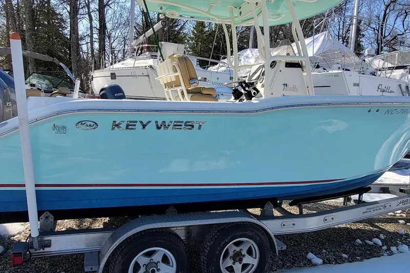 Slide: The Image of 2019 Key West 244 Center Console boat on trailer, light blue hull, parked outdoors. - 5