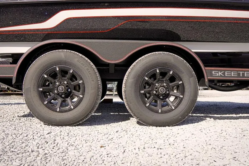Slide: The Image of 2026 Skeeter ZX200 trailer with dual black alloy wheels on gravel surface. - 10