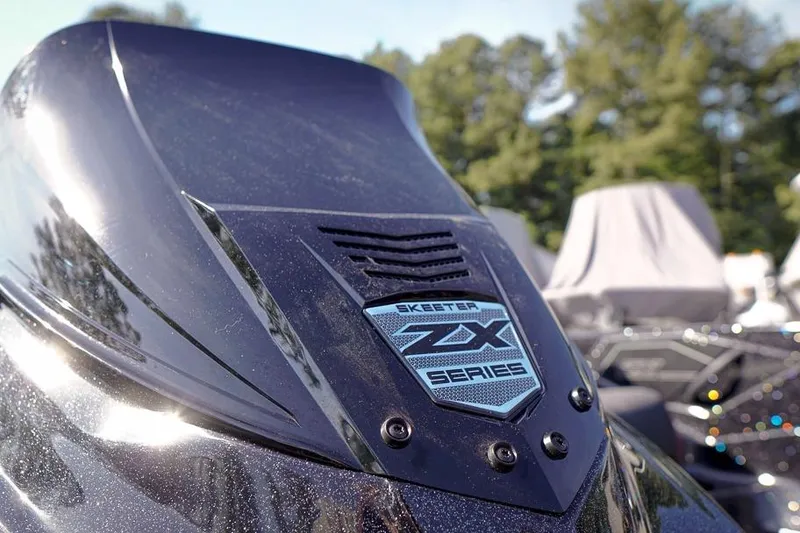 Slide: The Image of Close-up of 2026 Skeeter ZX200 boat badge with trees in the background. - 9