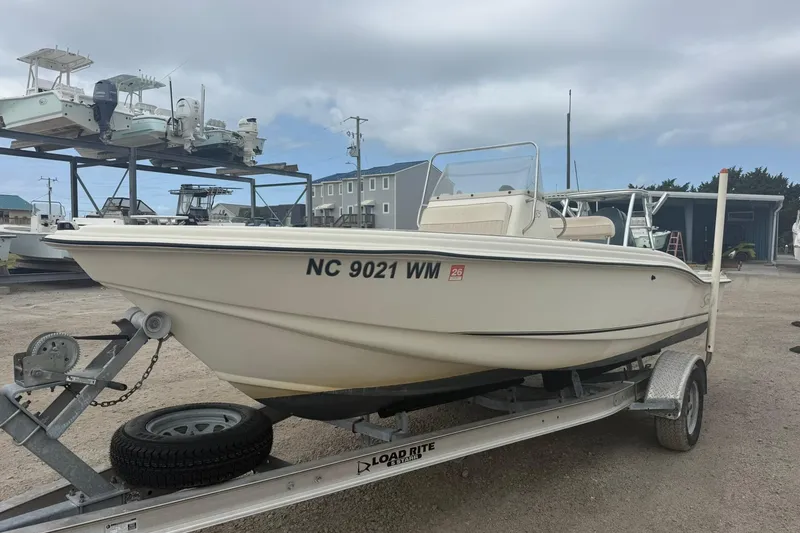 The Image of 2001 Scout 185 Sportfish boat on trailer, parked outdoors under cloudy sky. - 1