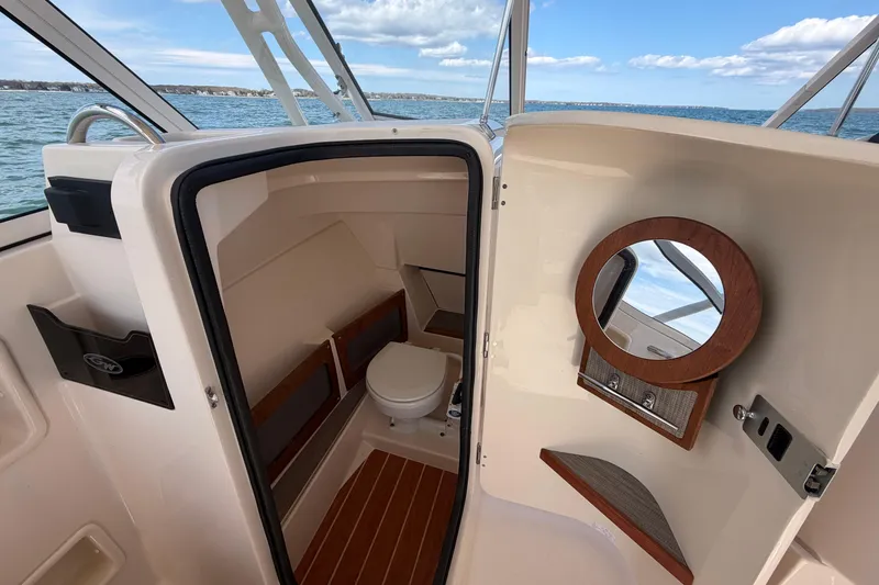 Slide: The Image of 2025 Grady-White Freedom 235 boat interior with compact bathroom and wooden accents. - 15