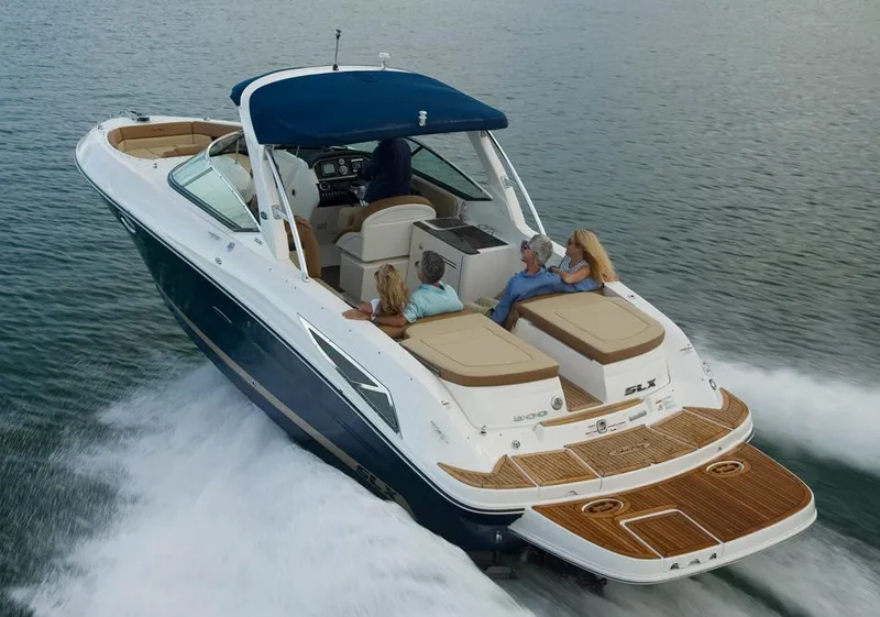 Slide: The Image of 2015 Sea Ray 300 SLX boat with covered seating, rear view, parked on gravel. - 2
