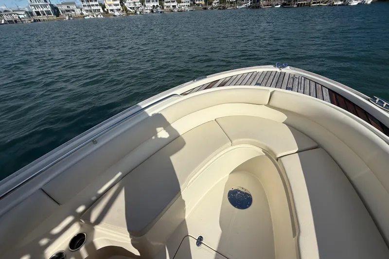 Slide: The Image of 2013 Chris-Craft Catalina 26 boat interior with cushioned seating, docked near waterfront homes. - 18
