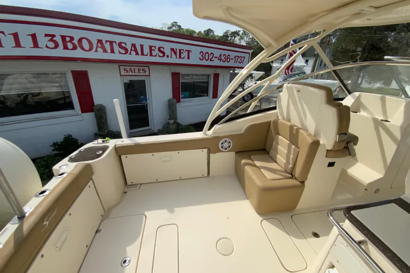 Slide: The Image of 2019 Scout 255 Dorado boat interior with beige seating, near a boat sales office. - 12