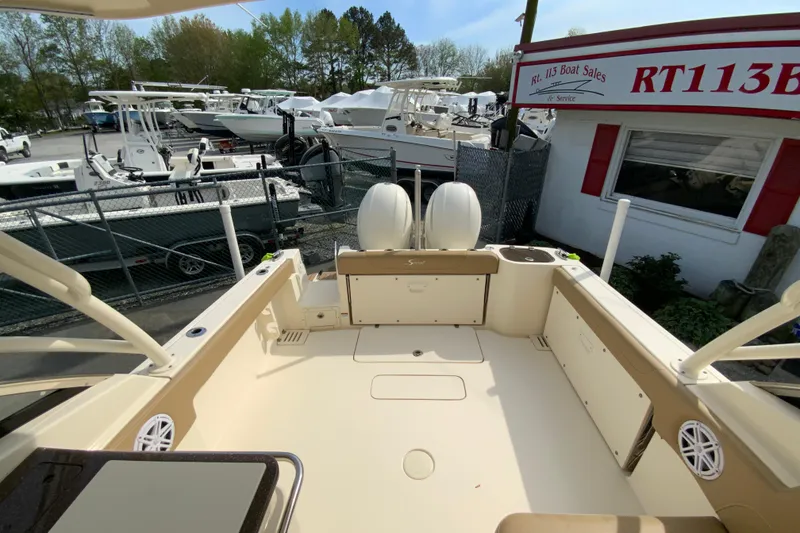 Slide: The Image of 2019 Scout 255 Dorado boat at dealership, showcasing spacious deck and dual engines. - 13