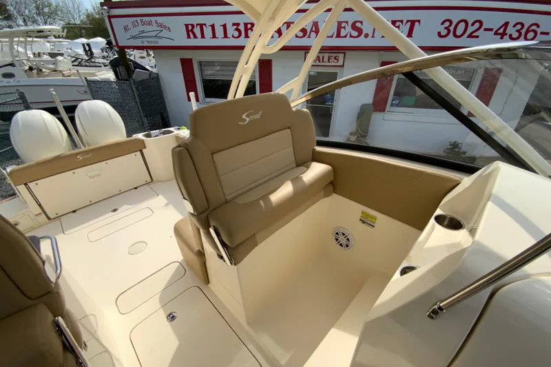 Slide: The Image of 2019 Scout 255 Dorado boat interior at dealership, featuring beige seating and helm area. - 18