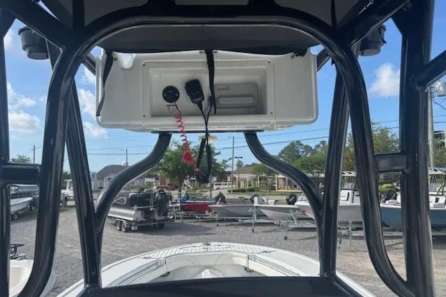 Slide: The Image of 2017 Yellowfin 26 Hybrid boat console with overhead electronics, parked in a marina. - 13