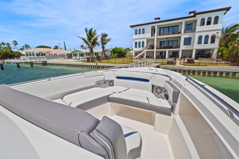 Slide: The Image of 2021 Tiara Sport 34 LS boat docked near waterfront homes, palm trees in background. - 20