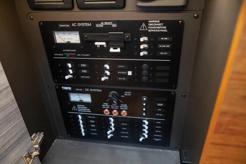 Slide: The Image of Electrical control panel on a 2021 Tiara Sport 34 LS boat, featuring AC and DC systems. - 64