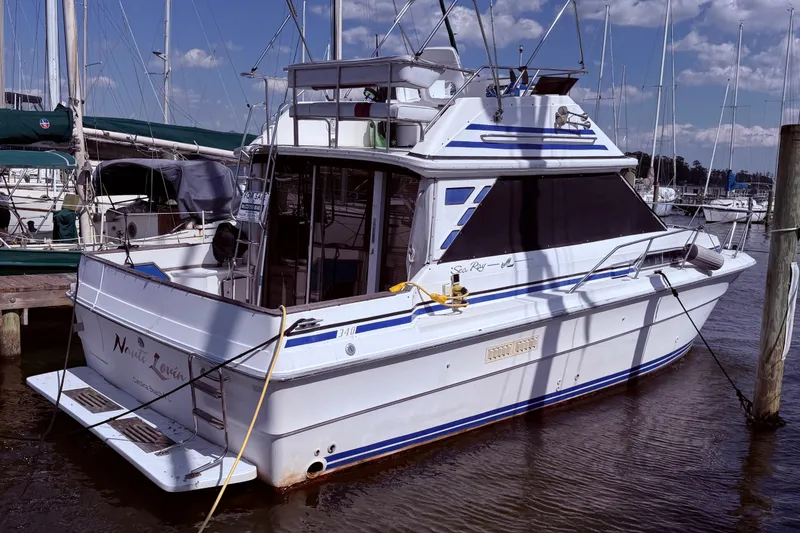 The Image of 1987 Sea Ray 340 Sedan Bridge yacht docked at marina, featuring sleek design and spacious deck. - 0