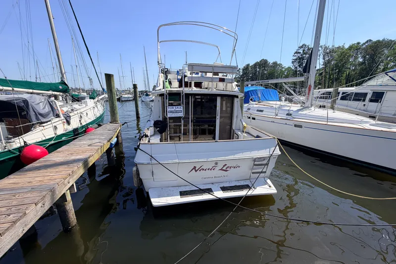 Slide: The Image of 1987 Sea Ray 340 Sedan Bridge docked, for sale sign visible, surrounded by other boats. - 2