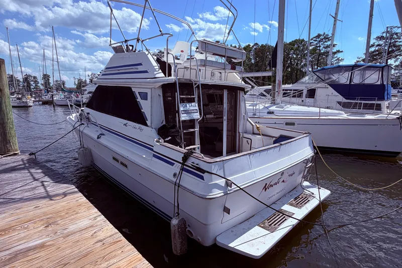 Slide: The Image of 1987 Sea Ray 340 Sedan Bridge docked, for sale, with clear skies and marina backdrop. - 3