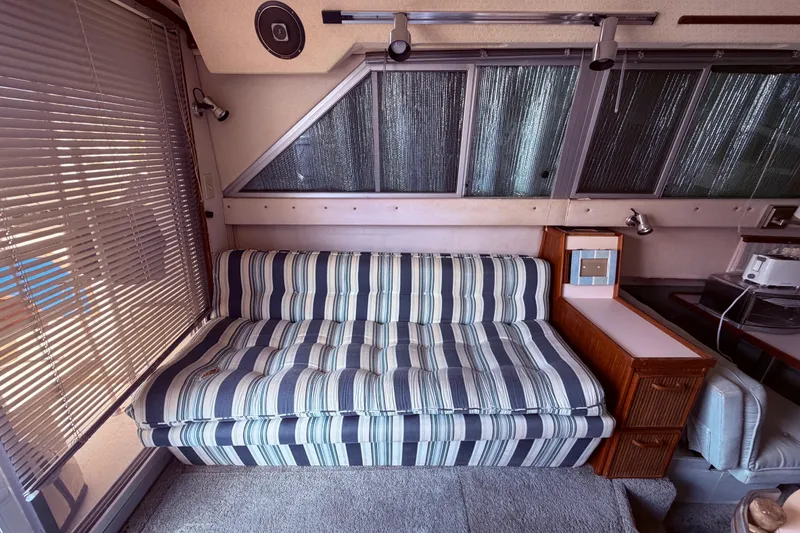Slide: The Image of Interior of 1987 Sea Ray 340 Sedan Bridge with striped sofa and wooden cabinetry. - 36