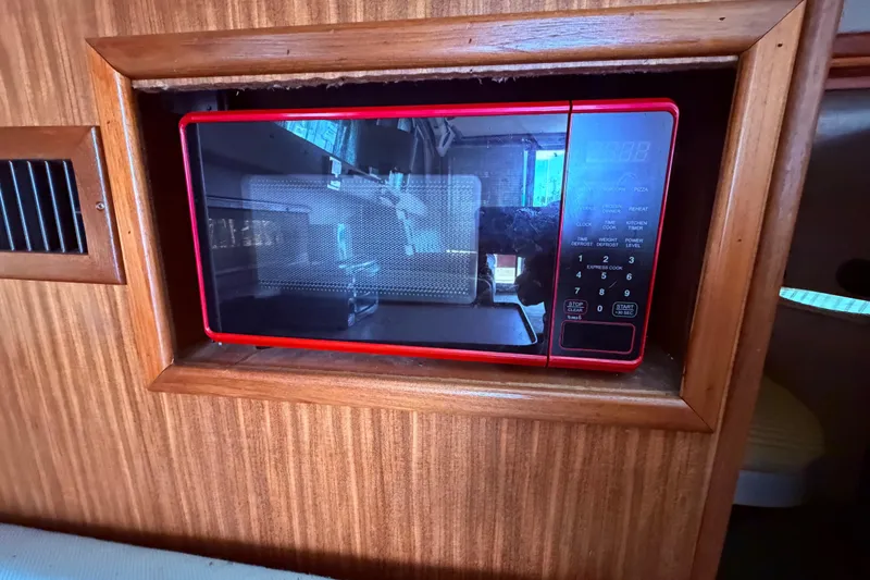 Slide: The Image of Red microwave in wooden cabinet on 1987 Sea Ray 340 Sedan Bridge boat. - 48