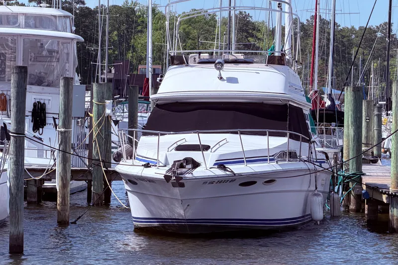 Slide: The Image of 1987 Sea Ray 340 Sedan Bridge docked at a marina, surrounded by other boats. - 5