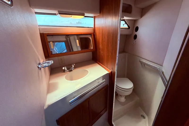 Slide: The Image of 1987 Sea Ray 340 Sedan Bridge bathroom with sink, mirror, and toilet. - 58