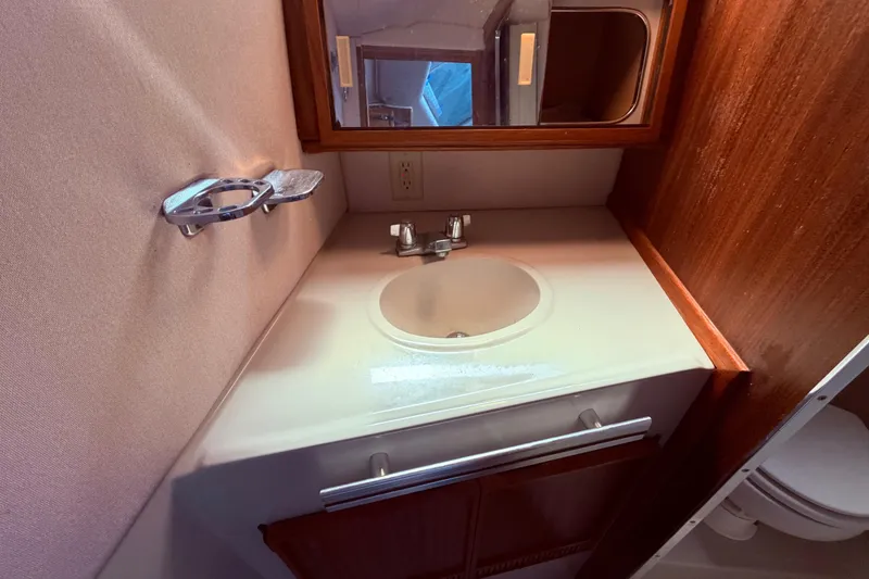 Slide: The Image of 1987 Sea Ray 340 Sedan Bridge bathroom with sink, mirror, and wooden cabinetry. - 59