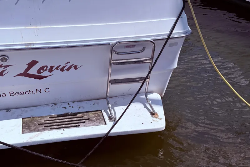 Slide: The Image of 1987 Sea Ray 340 Sedan Bridge stern with ladder and dock lines in water. - 6