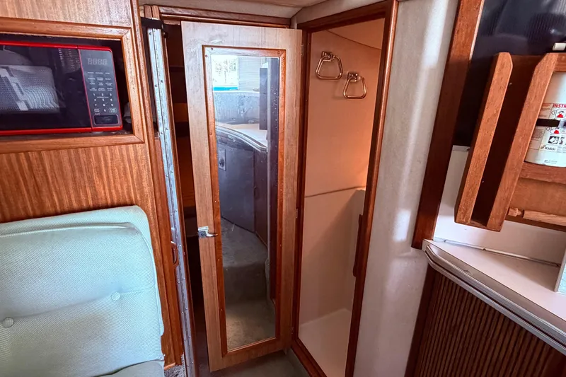 Slide: The Image of 1987 Sea Ray 340 Sedan Bridge interior with mirrored door to the bathroom, beyond this is the v berth - 64
